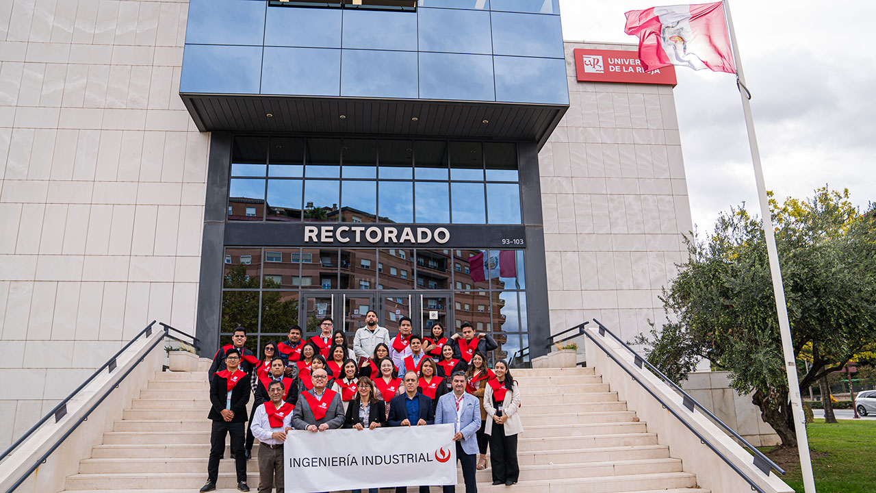 Foto de familia de los cursillistas en la escalinata del Edificio Rectorado con la bandera del Perú ondeando