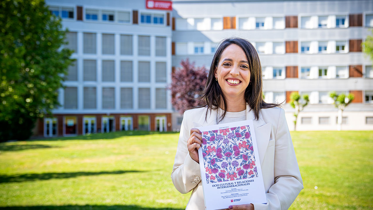 Cristina Medrano Pascual posa con el volumen de su tesis delante del Edificio Vives