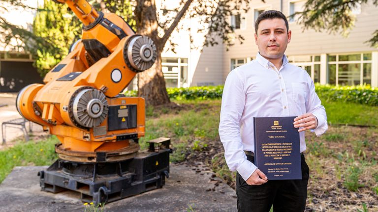 El doctor Jorge Los Santos Ortega posa con el volumen de su tesis en el patio de la Escuela Técnica Superior de Ingeniería Informática